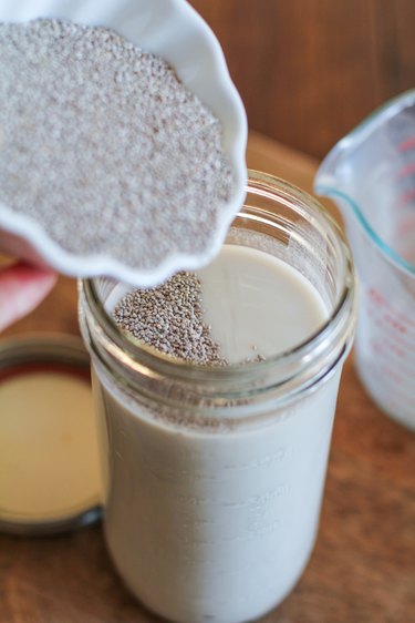 Pouring chia seed pudding ingredients into a jar