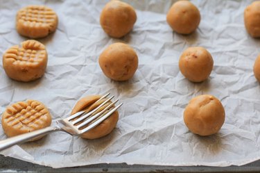 Fork making crisscross on cookie dough balls