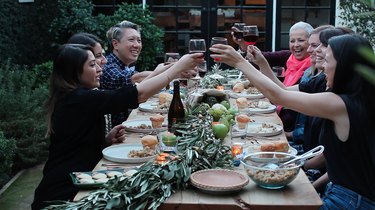 people toasting with wine glasses around a table