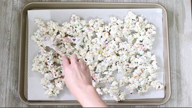 spreading rainbow popcorn on baking tray