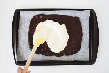 Using a spatula to spread the white chocolate.