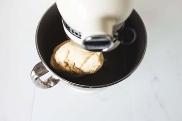 Mixing the dough to form a smooth ball.