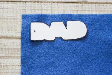 "DAD" cut out template placed on top of blue felt.