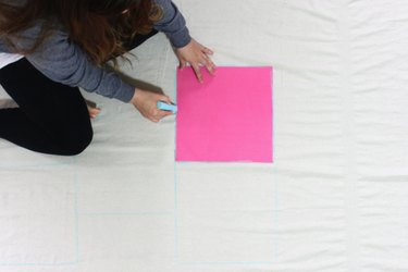 woman marking a drop cloth with chalk