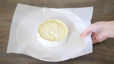 placing brie on parchment-lined plate