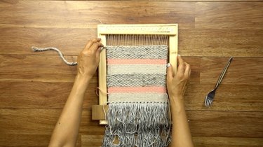 Weaving horizontal stripes on woven wall hanging.