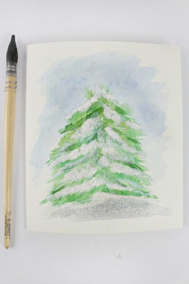 A watercolor of a snow-topped tree.