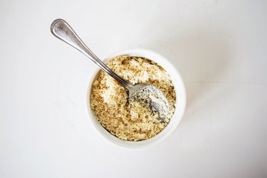 Breadcrumbs in a small bowl with a spoon.