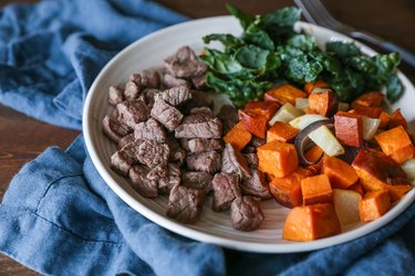 Beef on a plate with sweet potatoes and kale salad