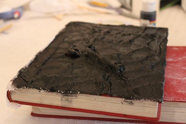 Black acrylic paint over the entire cover of the book.