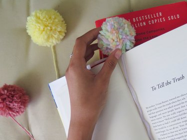 Place the yarn pompom at the top of the book page.
