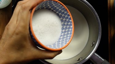 Adding sugar-free sweetener to heavy cream in saucepan for sugar-free Irish cream liqueur.