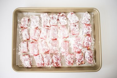 Baking tray filled with Turkish delight pieces coated in powdered sugar.
