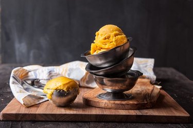 A stack of silver bowls topped with a scoop of mango ice cream