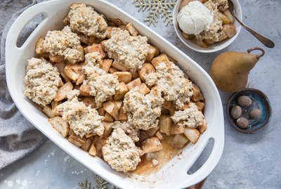 casserole dish of pear cobbler with a bowl of pear cobbler and a fresh pear