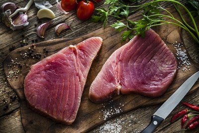 Two raw tuna steaks on rustic wooden table