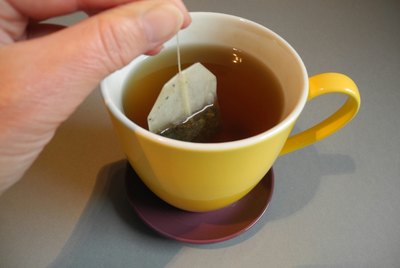Cropped Hand Dipping Teabag In Cup At Home