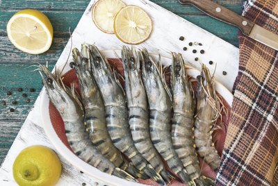 Fresh raw tiger prawns and spices on wooden table