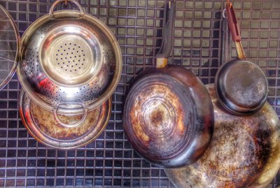Saucepans And Kitchen Utensils Hanging On Backsplash At Home
