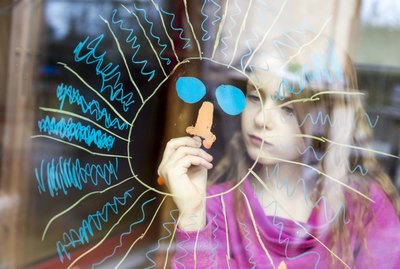 Girl painting sun on windowpane