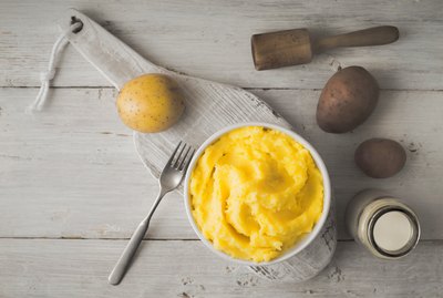 Mashed potatoes in bowl on white wooden table top view