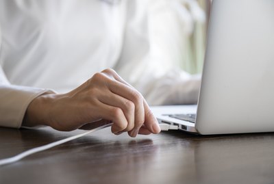 Hand of a woman plugging the cord into the USB of the personal computer