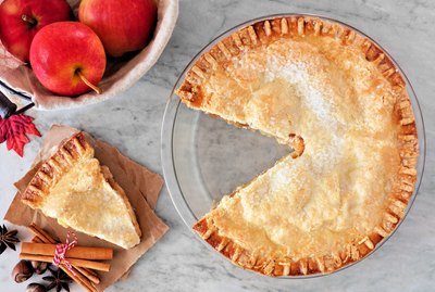 Apple pie, overhead scene with cut slice on marble background