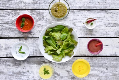Bowl of salad leaves with various salad dressings