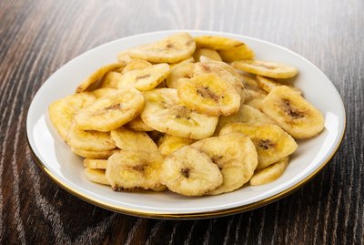 Banana chips in saucer on wooden table