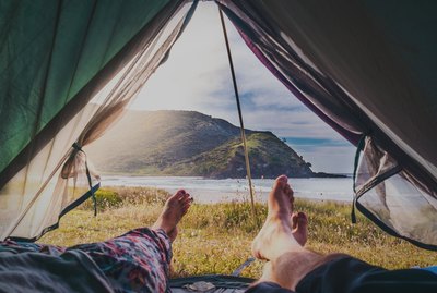 Low Section Of People Lying In Tent Against Mountain And Sea