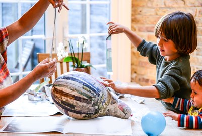 Child and mother playing with papier mache