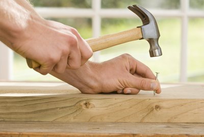 Hands hammering nail into wood