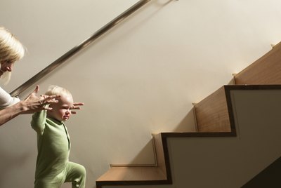 Mother helping baby boy walk up stairs
