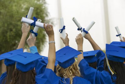 Group of Graduates Dressed in Graduation Gowns Holding Scrolls in the Air
