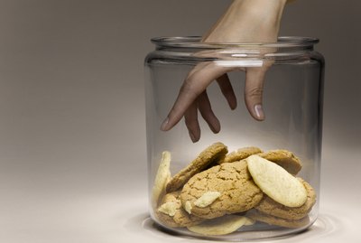 Woman reaching for cookies in cookie jar, close-up of hand