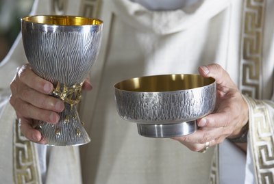 Priest holding goblet and communion bowl
