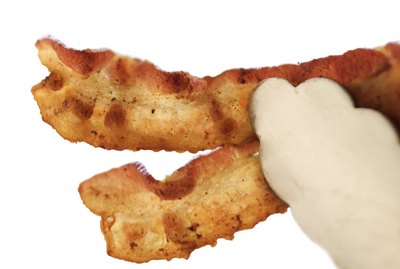 Tongs holding bacon