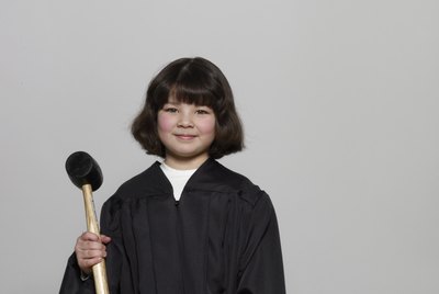Girl (5-7) wearing judicial robe, holding gavel, portrait