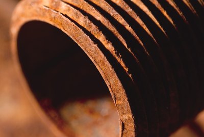 a close-up of a rusted steel pipe lying on other rusted steel pipes