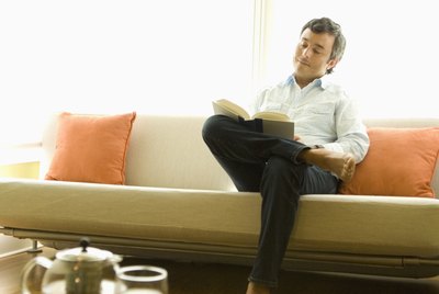 Hispanic man reading on sofa