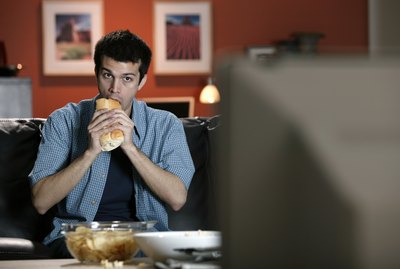 Man eating sandwich and watching television