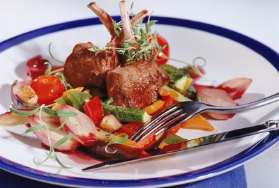 Roasted meat with vegetables on plate, close-up