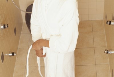 Woman wearing bathrobe standing in shower, elevated view