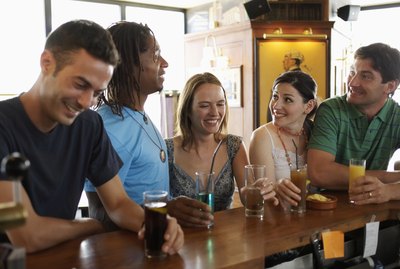 Group of friends standing at bar, smiling