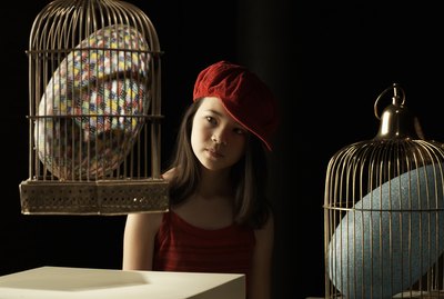 Girl (10-11) looking at giant colorful egg in cage