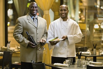 African male restaurant staff holding food and wine