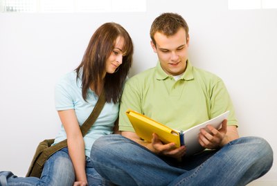 Teenage boy and girl sitting on floor reading together