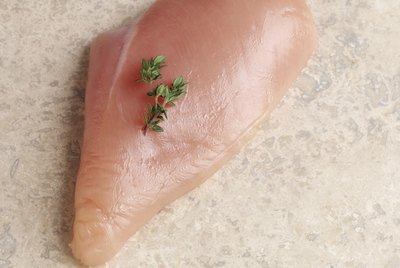 Raw chicken breast with parsley garnish