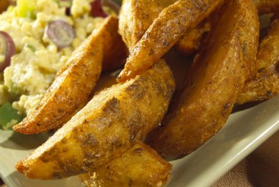 Close-up of potato wedges with scrambled eggs on a tray