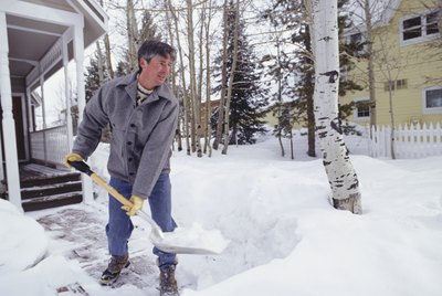 Man shovelling snow from walkway outside house